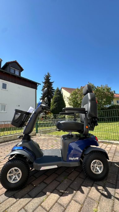 Schwarz-blauer Elektromobil mit drei Rädern auf gepflastertem Boden, im Freien.